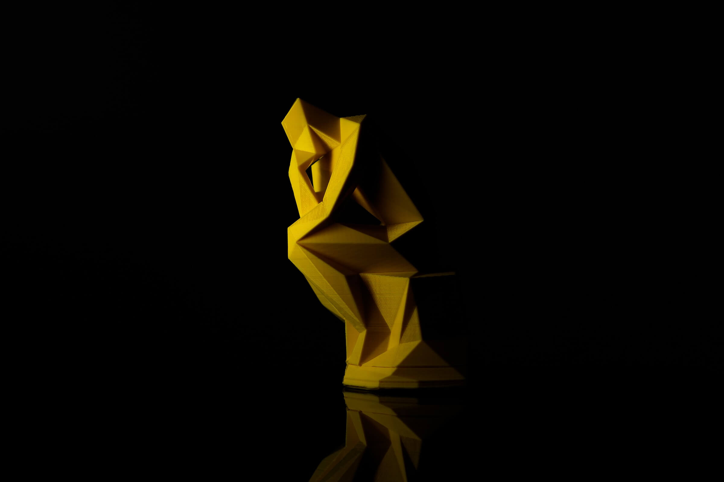 Yellow Sculptural Model of Man with Chin on Hand Against Black Background